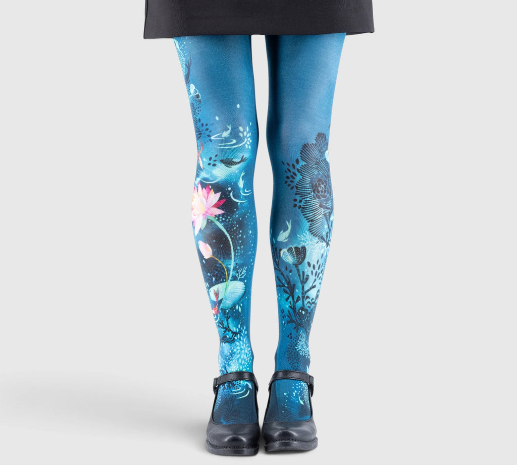 Jambes féminines portant des collants bleus imprimés motifs floraux et marins, chaussures noires à bride, pantalon noir