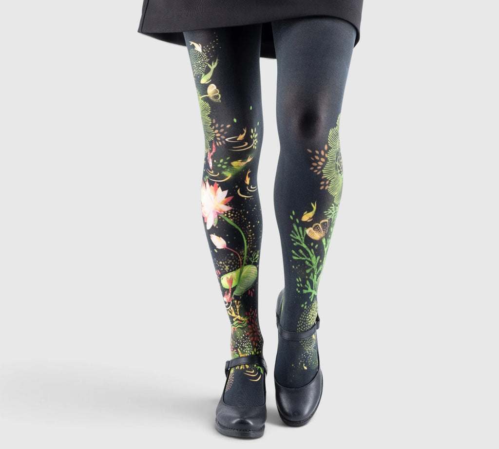 Jambes de fille portant des collants noirs ornés de motifs floraux lumineux et poissons, avec chaussures noires à bride.