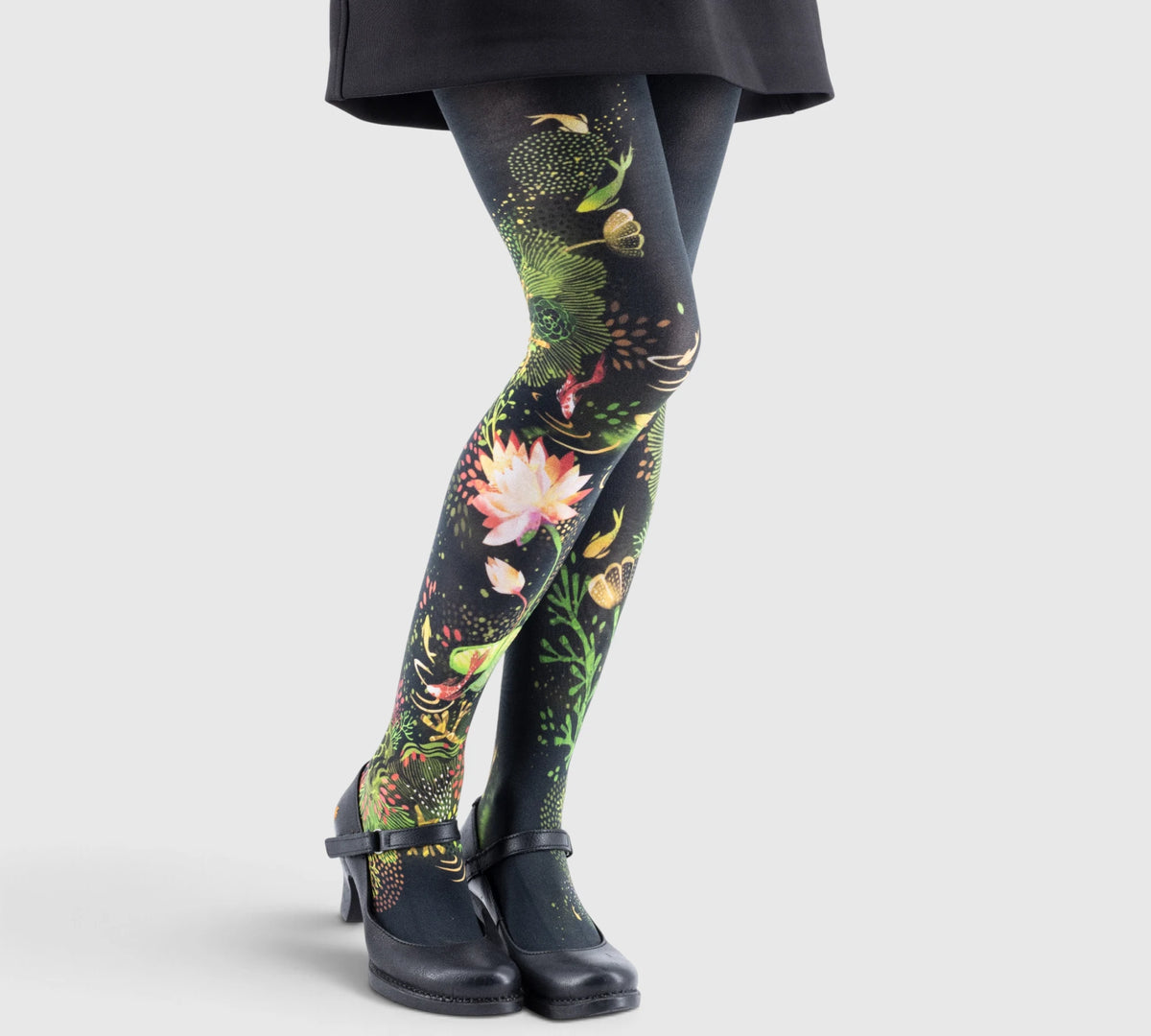 Leggings imprimés floraux volumineux sur fond noir, associées à des chaussures noires à petits talons et brides.